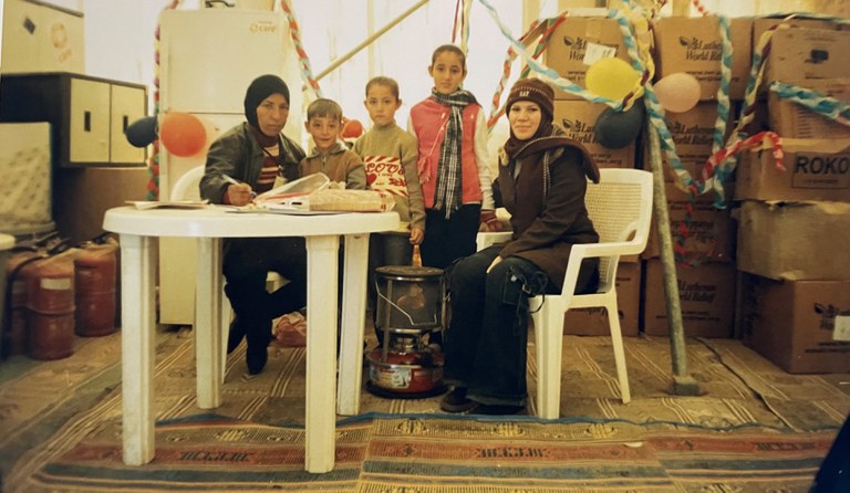 Shahen and some family members meet with an NGO staff member around a table.